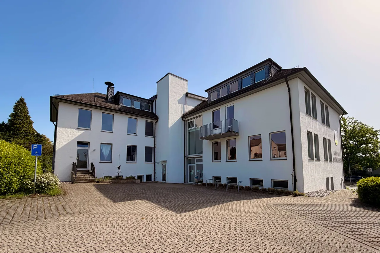 Das mehrstöckige, weiße Rathaus Breckerfeld mit dunklem Dach und einem gepflasterten Vorplatz.