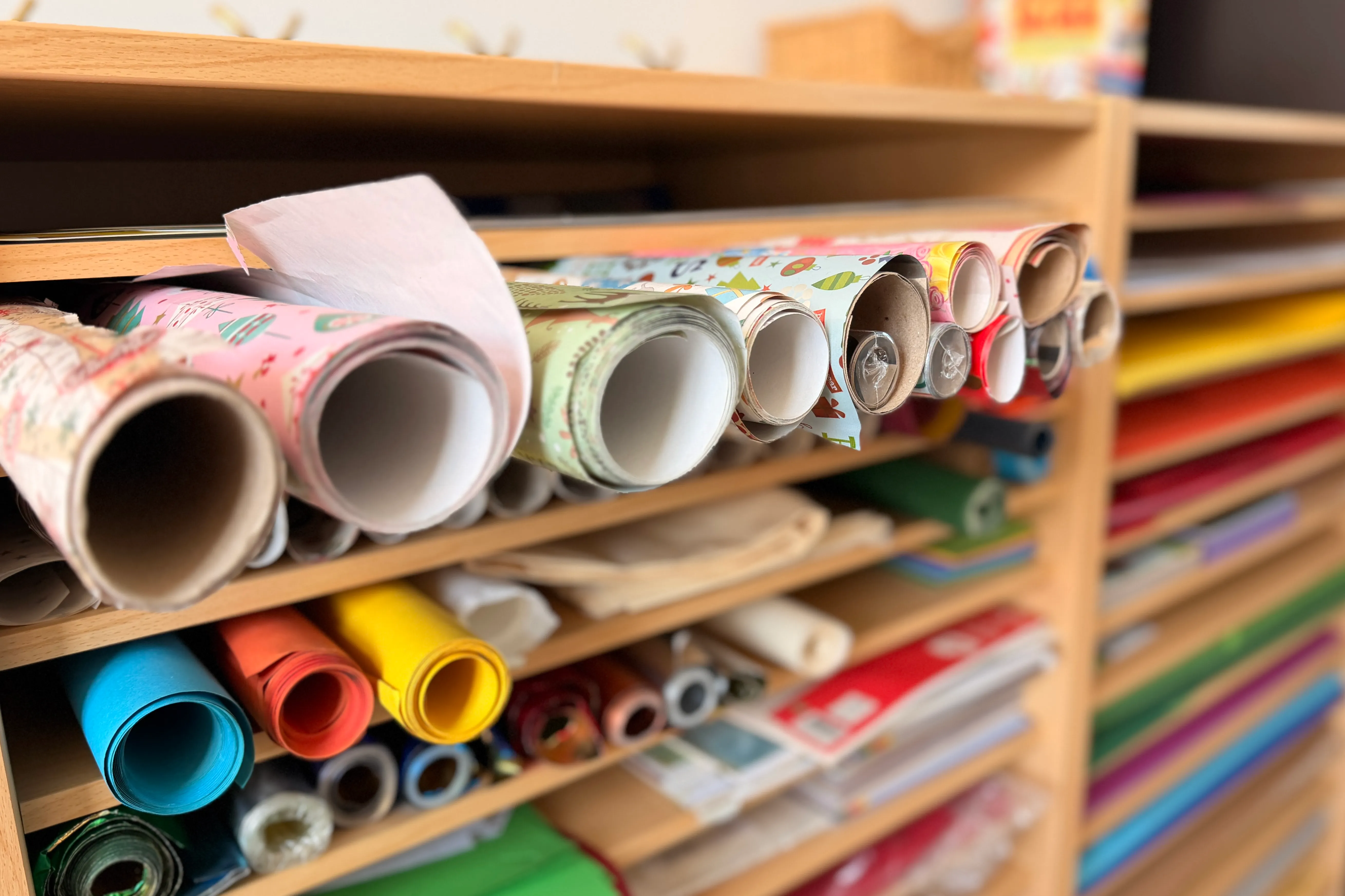 Regale gefüllt mit Rollen buntem Geschenkpapier und Bastelmaterialien im Jugendzentrum.