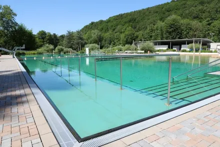 Das geöffnete Freibad Kluterbad Ennepetal mit türkisfarbenem Wasser und metallischen Bahnenmarkierungen.