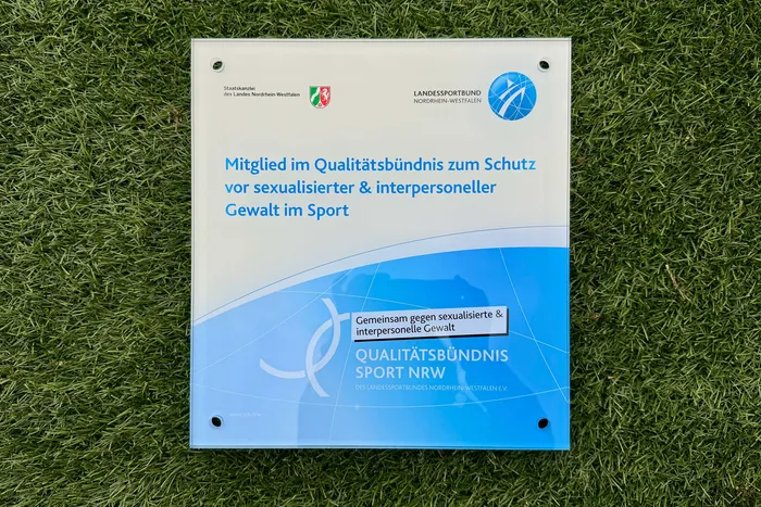 Schild des Landessportbundes Nordrhein-Westfalen mit dem Hinweis auf das Qualitätsbündnis zum Schutz vor sexualisierter und interpersoneller Gewalt im Sport.