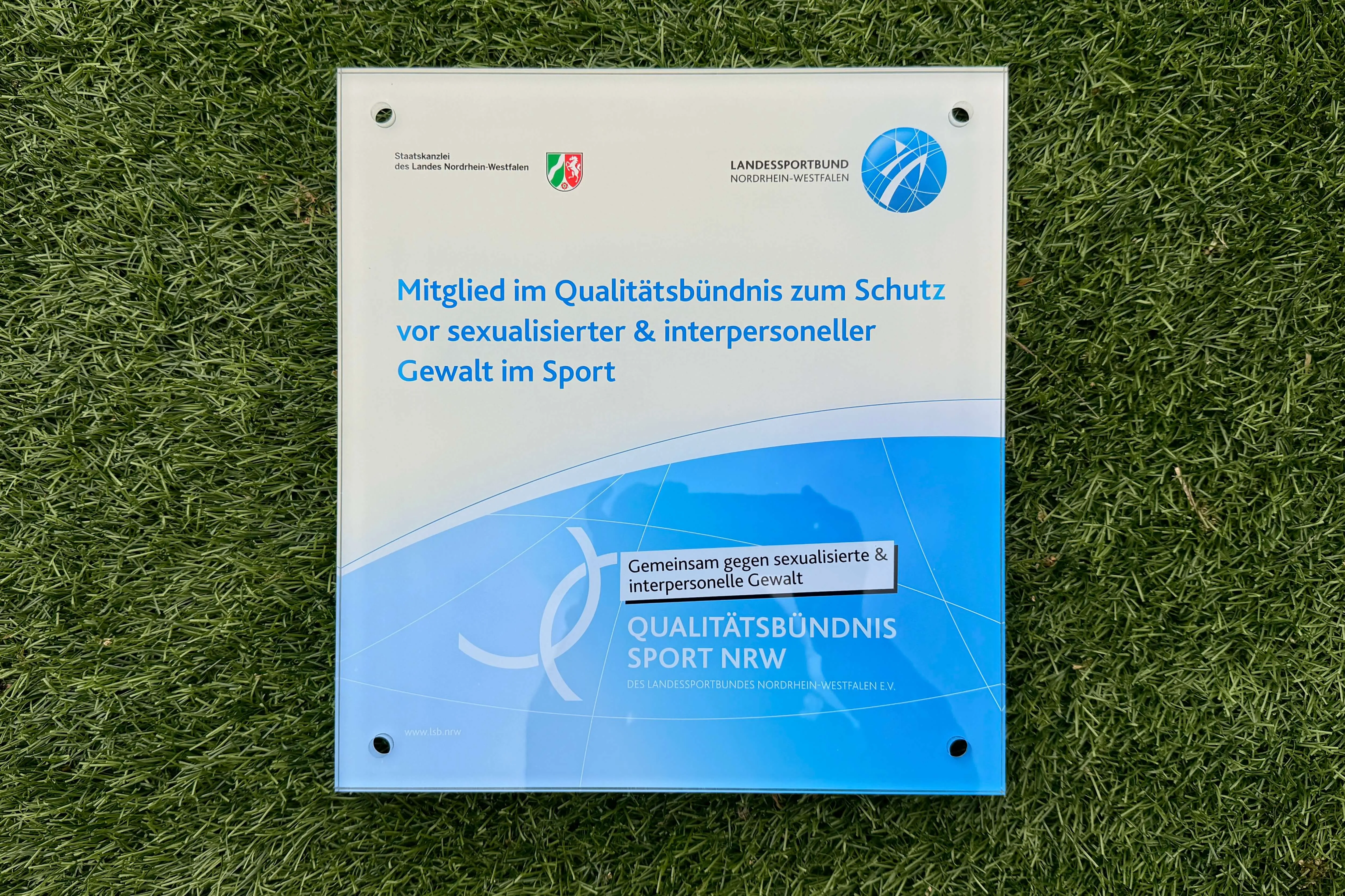 Schild des Landessportbundes Nordrhein-Westfalen mit dem Hinweis auf das Qualitätsbündnis zum Schutz vor sexualisierter und interpersoneller Gewalt im Sport.