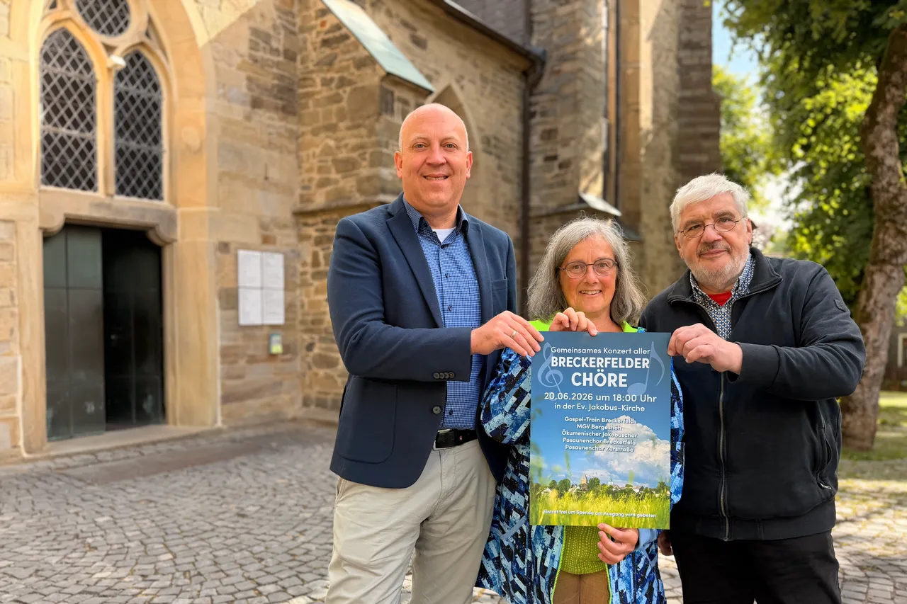 André Dahlhaus, Ute Slotkowski und Friedbert Schulz stehen vor der Jakobus-Kirche und halten eine Ankündigung für ein gemeinsames Konzert der Breckerfelder Chöre am 20. Juni um 18:00 Uhr.