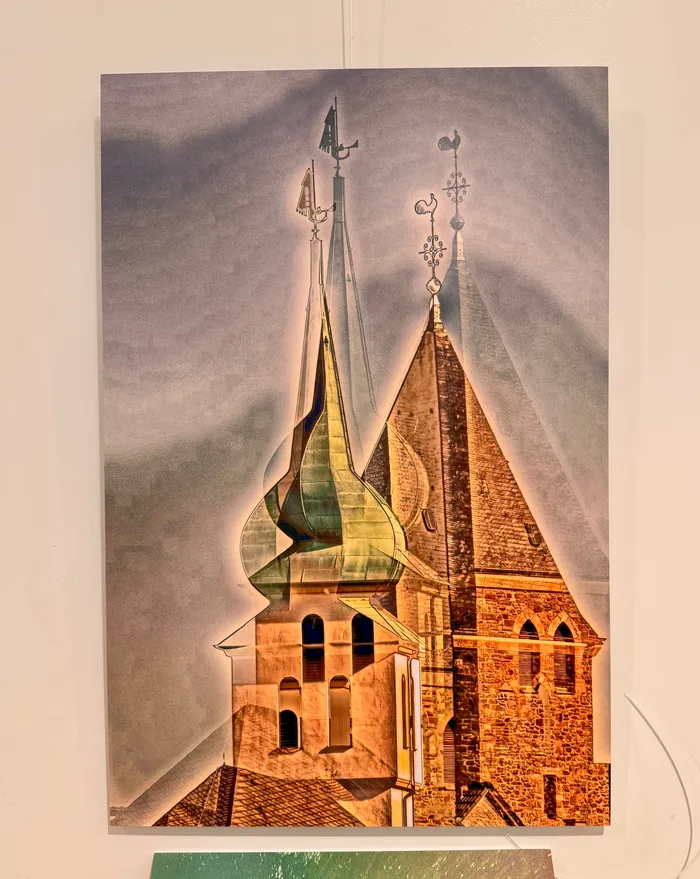 Das Bild zeigt einen Turm mit mehreren spitzen Dachaufsätzen und Windfahnen. Der Backsteinbau ist von einem dunstigen Himmel umgeben.