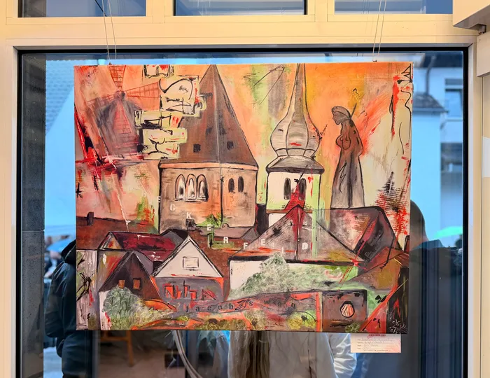 Abstrakte Malerei zeigt eine stilisierte Stadtansicht mit Kirche und Häusern in warmen Farben, dominiert von Rot-, Orange- und Gelbtönen. Im Vordergrund sind grobe Pinselstriche und angedeutete Figuren zu erkennen.