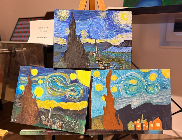 Drei Gemälde im Stil von Vincent van Gogh, darunter eine stilisierte Zypresse und ein Sternenhimmel über einem Dorf, sind auf Ständern ausgestellt. Im Hintergrund ein Schild mit der Aufschrift „Klasse 10 A/B Kunstkurs Freie Malerei“.