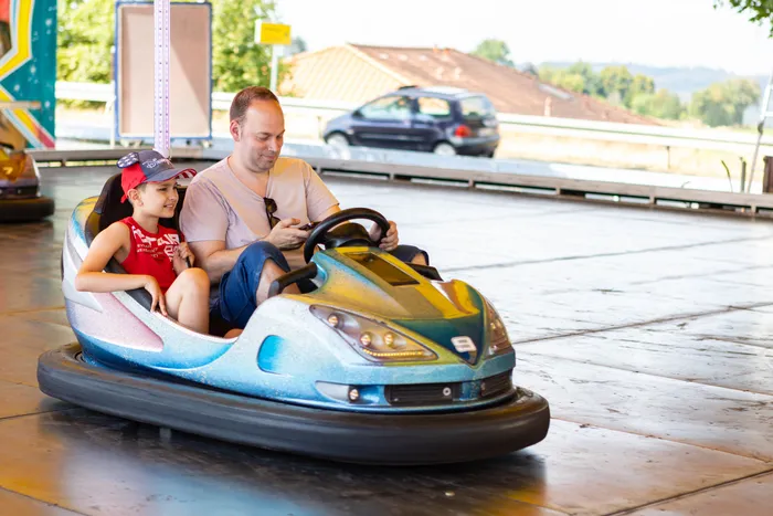 Ein Mann und ein kleiner Junge sitzen in einem blauen Bumper Car.