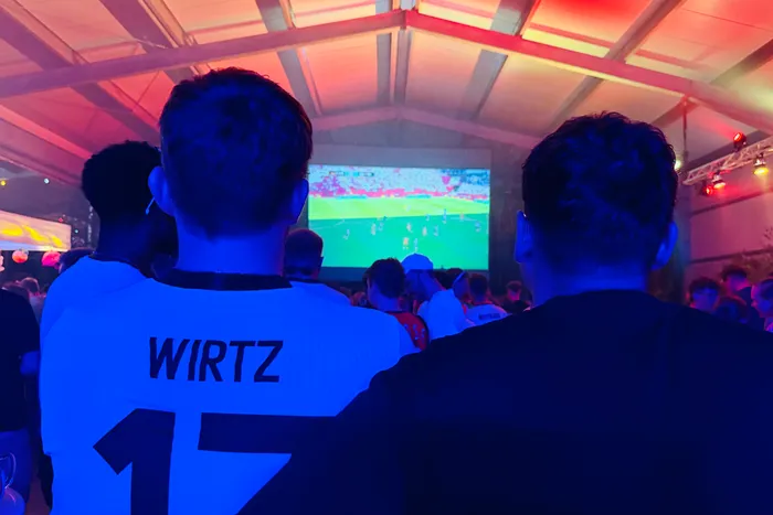 Zwei Personen mit Trikots, auf denen 
