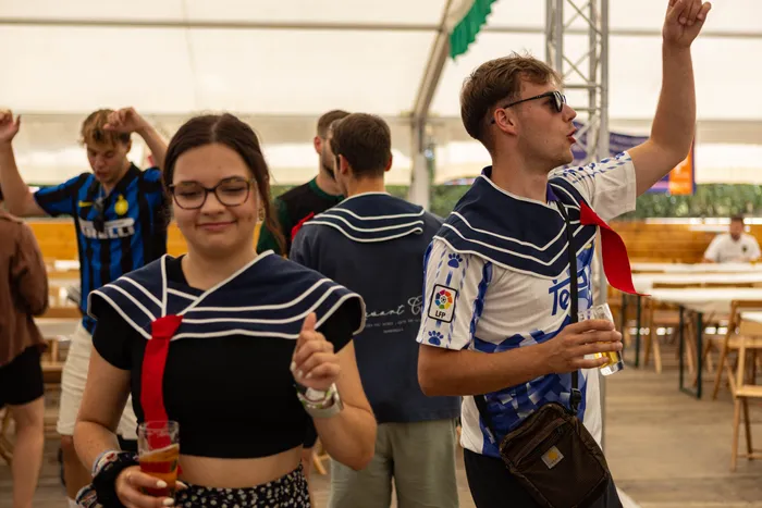 Junge Menschen tragen blau-weiß gestreifte Matrosenkragen mit roten Krawatten bei einer Feier des Schützenfests.