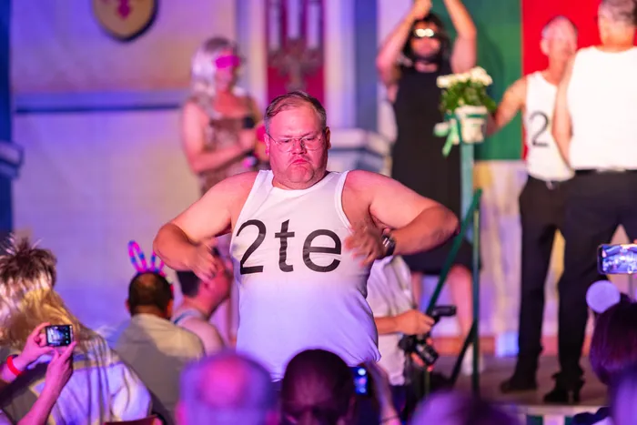 Ein Mann in einem weißen Tanktop mit der Aufschrift „2te“ tanzt auf einer Bühne beim Schützenfest.