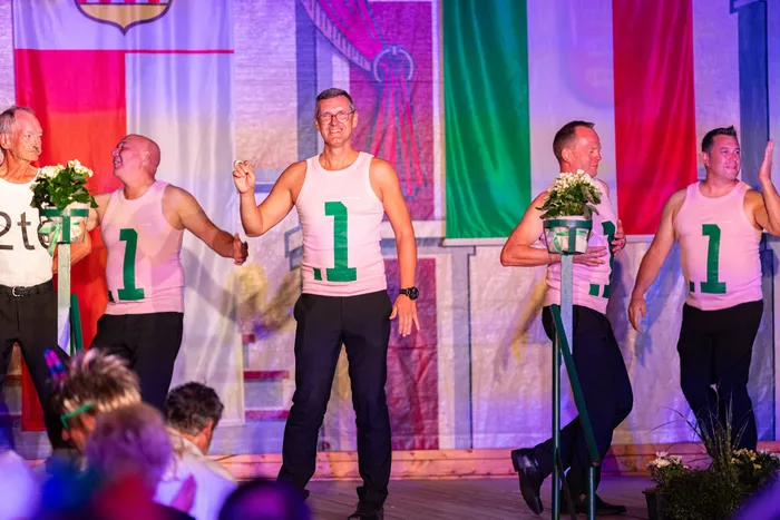 Männer in rosa Tanktops mit der grünen Zahl 1 tanzen auf einer Bühne beim Schützenfest.