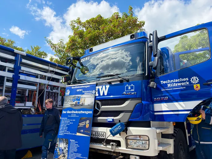 Blauer Lastwagen der Technischen Hilfswerke mit der Aufschrift 'Gerätekraftwagen GKW' und dem Logo der Verkehrswacht Lüdenscheid. Im Hintergrund ein weiterer blauer THW-Lastwagen.