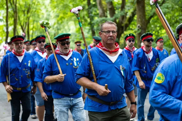 Schützen marschieren mit Gewehren und Blumen im Schützenfest-Sonntag in Meinerzhagen.