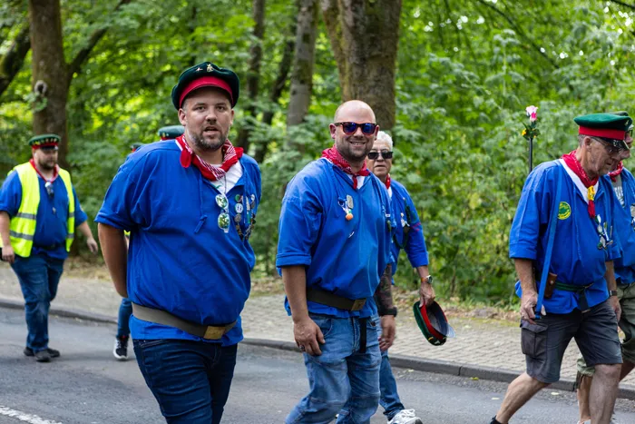 Mehrere Männer in traditioneller Kleidung gehen auf einer Straße, einige blicken in die Kamera.