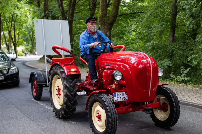 Ein Schützenprinz fährt auf einem roten Oldtimer-Traktor durch Meinerzhagen.