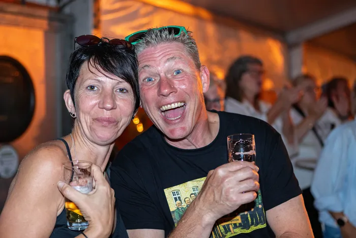 Ein lachender Mann und eine lächelnde Frau halten Gläser mit Getränken in den Händen während des Schützenfests.