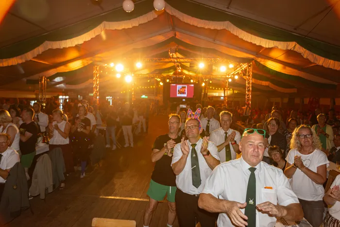 Eine Menschenmenge klatscht in einem hell erleuchteten Festzelt während des Schützenfestes.