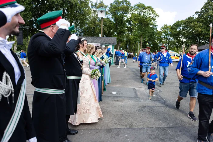 Schützenfestzug in Meinerzhagen mit Trachtengruppen, Musikern und einem jungen Schützenläufer.