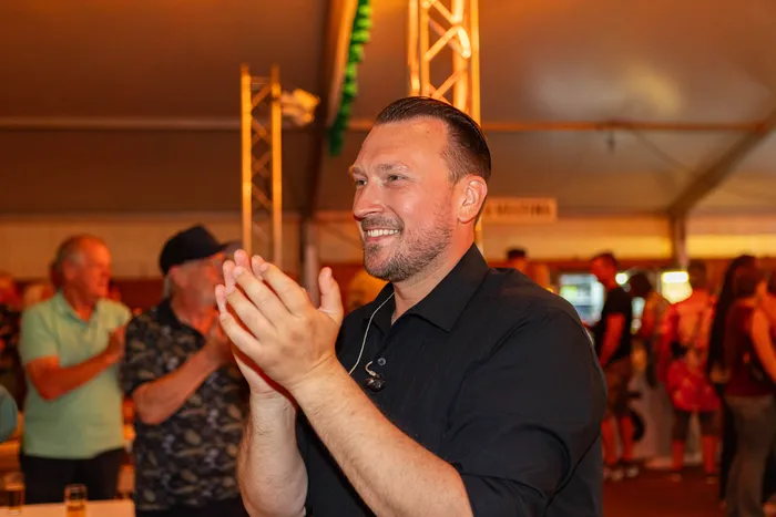 Ein lächelnder Mann im schwarzen Hemd klatscht während des Schützenfests der Hülscheider Schützen.