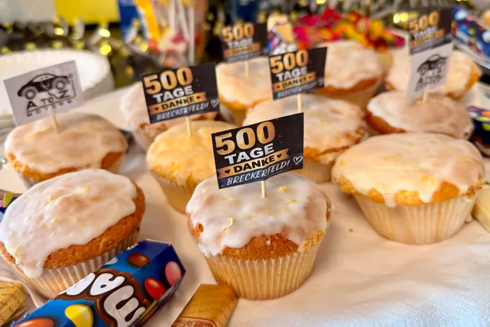 Muffins mit weißem Guss und kleinen schwarzen Schildern mit der Aufschrift „500 TAGE DANKE BRECKERFELD!“ und „A to Z MOTORS“.