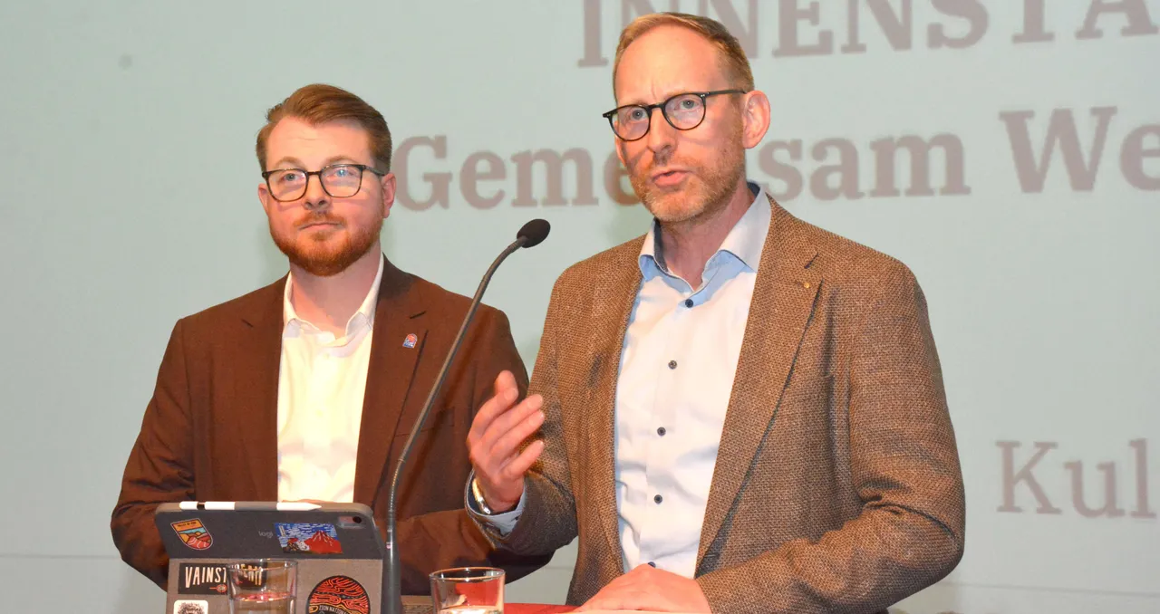 Manuel Bunge-Altenberg und Oliver Fröhling stehen hinter einem Rednerpult mit Mikrofon.