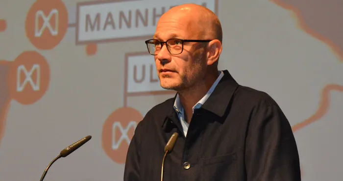 Dr. Kevin Meyer, Geschäftsführer von Midstad, blickt bei einem Infoabend zur Seite. Ein Mikrofon ist im Vordergrund zu sehen.