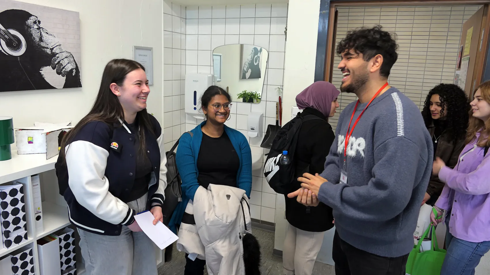 Schüler und Ausbildungsvertreter stehen in einem Flur des Albert-Schweitzer-Gymnasiums Plettenberg und unterhalten sich angeregt. Im Hintergrund sind Infostände und ein Spiegel zu sehen.