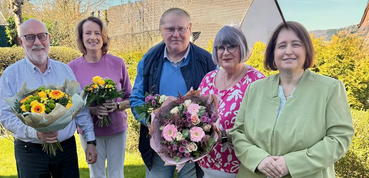 Fünf lächelnde Menschen stehen im Freien und halten Blumensträuße. Im Mittelpunkt des Bildes stehen Dörte Kaul-Hentschel und ihr Mann Matthias Hentschel.