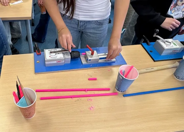 Zwei Schülerinnen arbeiten an einem Bauprojekt mit pinkfarbenen Stäben und Werkzeugen auf einem Tisch im Technikzentrum Südwestfalen.