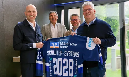 Vier Männer halten ein Eishockeytrikot mit dem Aufdruck 'Schlüter-Systems 2028' und dem Logo der Märkischen Bank. Von links: Frank Richter, Wolfgang Brück, Marc und Udo Schlüter.