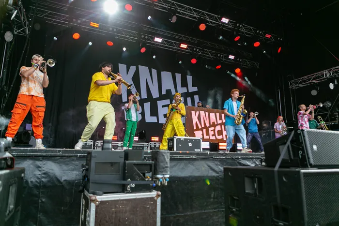 Die Band Knallblech spielt mit verschiedenen Blasinstrumenten auf einer beleuchteten Bühne beim Bautz Festival.