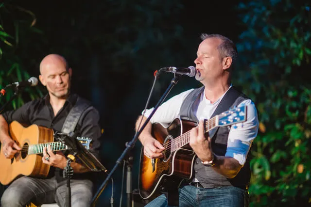 Tobias Janssen und George Schneider spielen akustische Gitarren und singen bei einem Live-Auftritt.