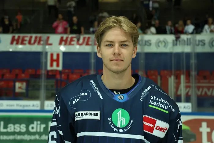 Johannes Krauss in einem dunkelblauen Eishockeytrikot mit Sponsorenlogos.