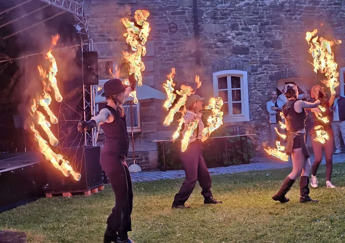 Zwei Feuerkünstlerinnen mit brennenden Fächern vor dem Schloss Neuenhof während einer Jubiläumsfeier.