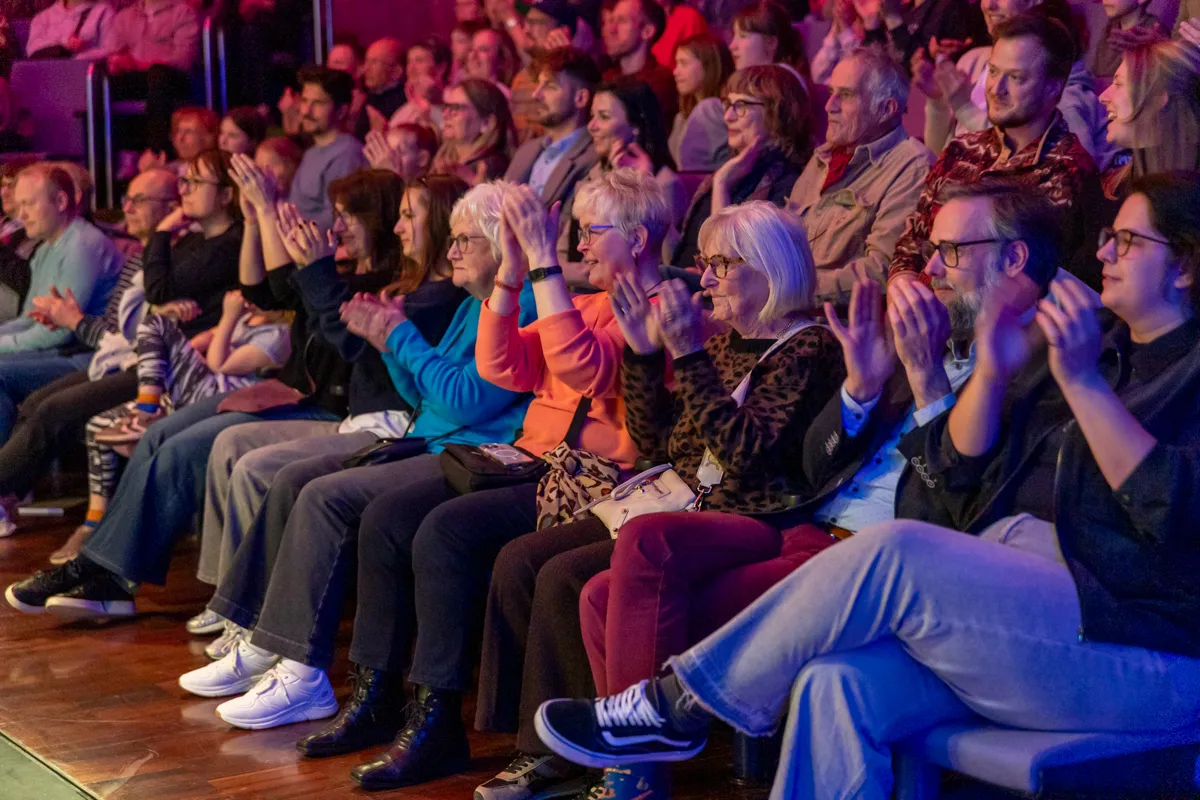 Zuschauer klatschen begeistert in einem dunklen Theatersaal während der Premiere der Show „Kaskadia“.