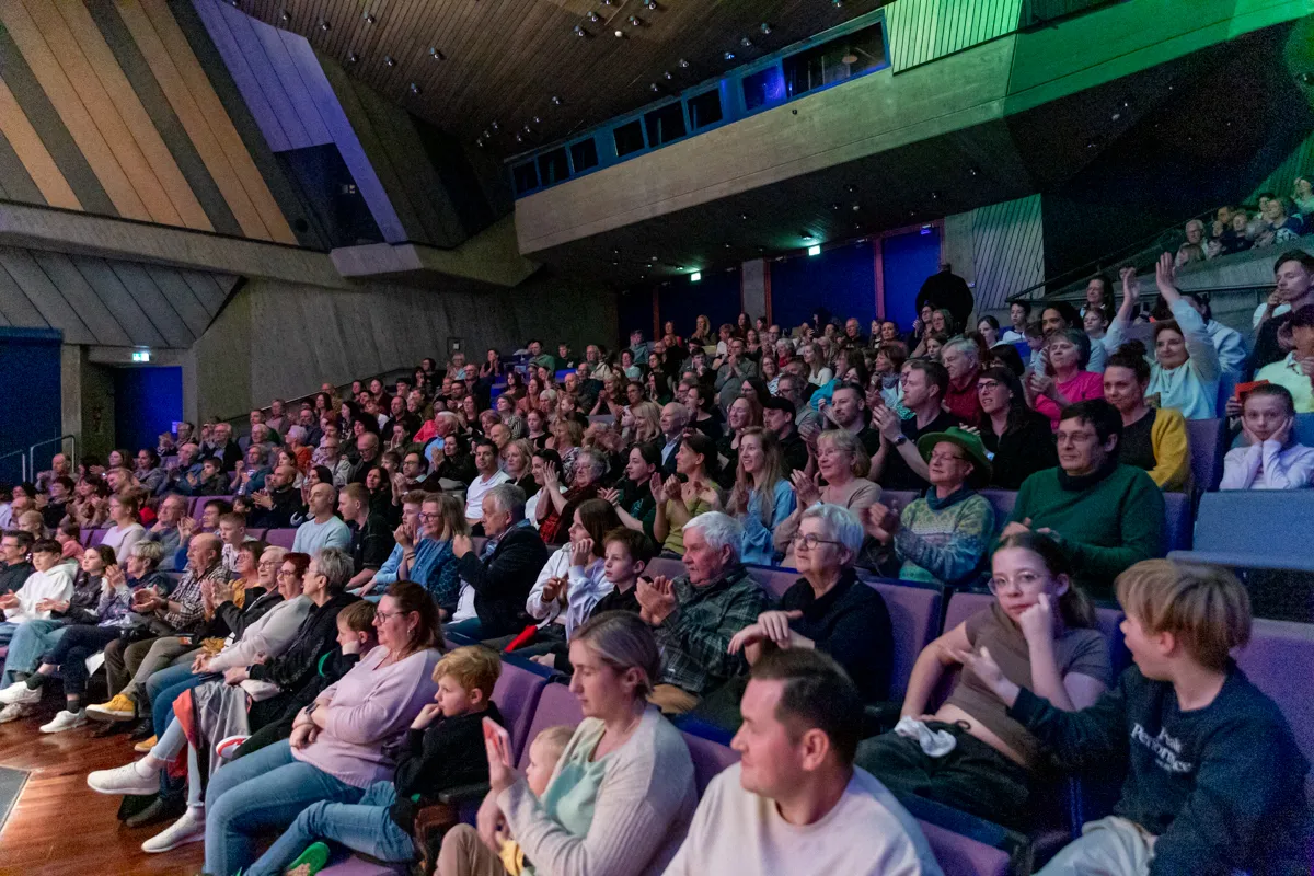 Zuschauer in einem voll besetzten Theatersaal applaudieren und lächeln während der Premiere der Show „Kaskadia“.