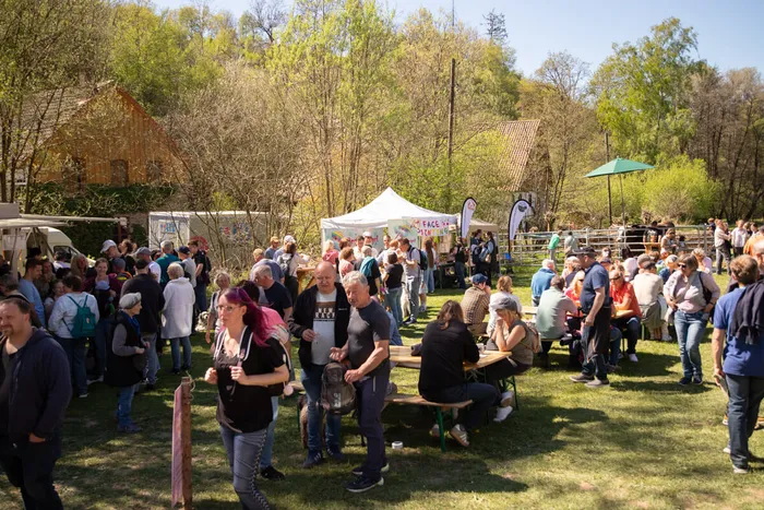 Volksfest mit vielen Besuchern an Biertischen und Buden vor ländlichem Hintergrund.