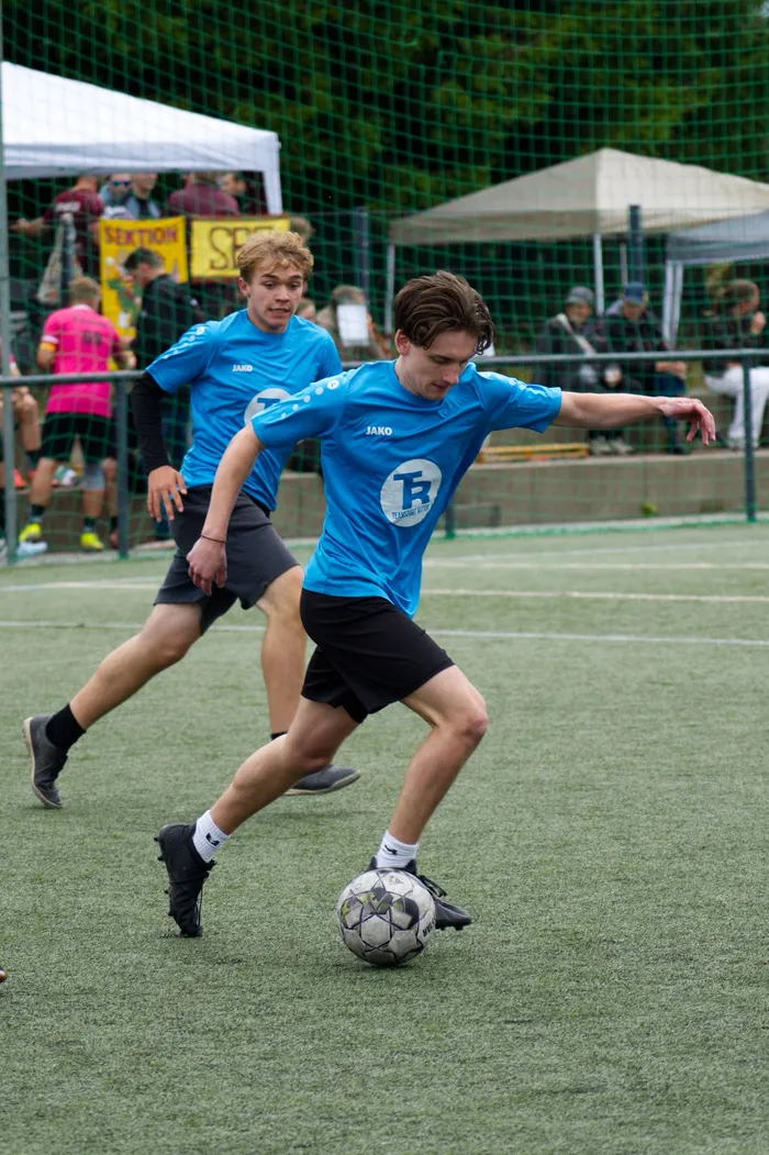 Zwei junge Fußballspieler in blauen Trikots mit dem Logo 