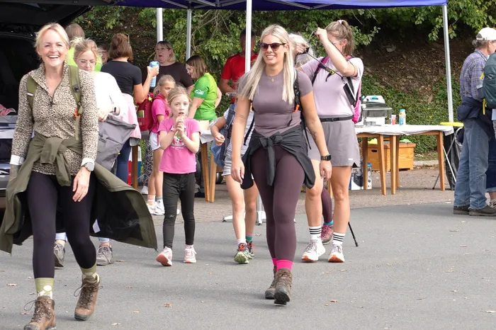 Lächelnde Teilnehmer in Wanderkleidung gehen bei einer kulinarischen Wanderung in Herscheid über einen asphaltierten Weg.