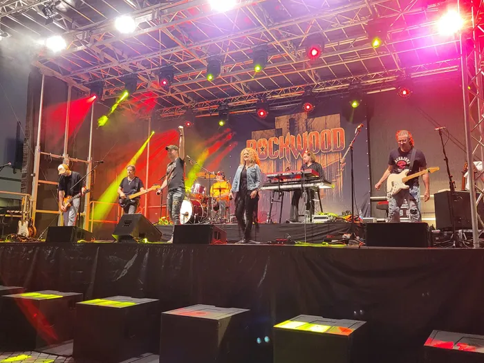 Die Coverband Rockwood spielt live auf einer Bühne unter farbenfroher Scheinwerferbeleuchtung.