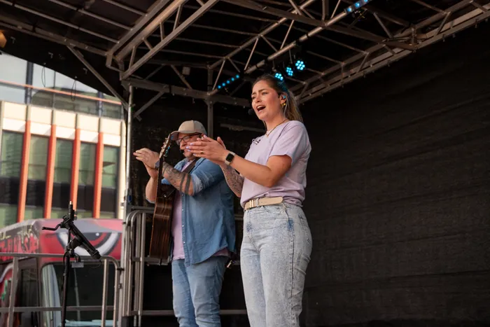Sängerin mit Mikrofon und Gitarrist auf einer Bühne vor Publikum bei einem Stadtfest.