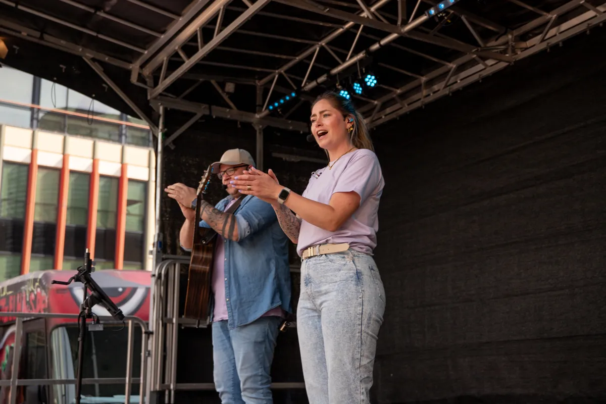 Sängerin mit Mikrofon und Gitarrist auf einer Bühne vor Publikum bei einem Stadtfest.