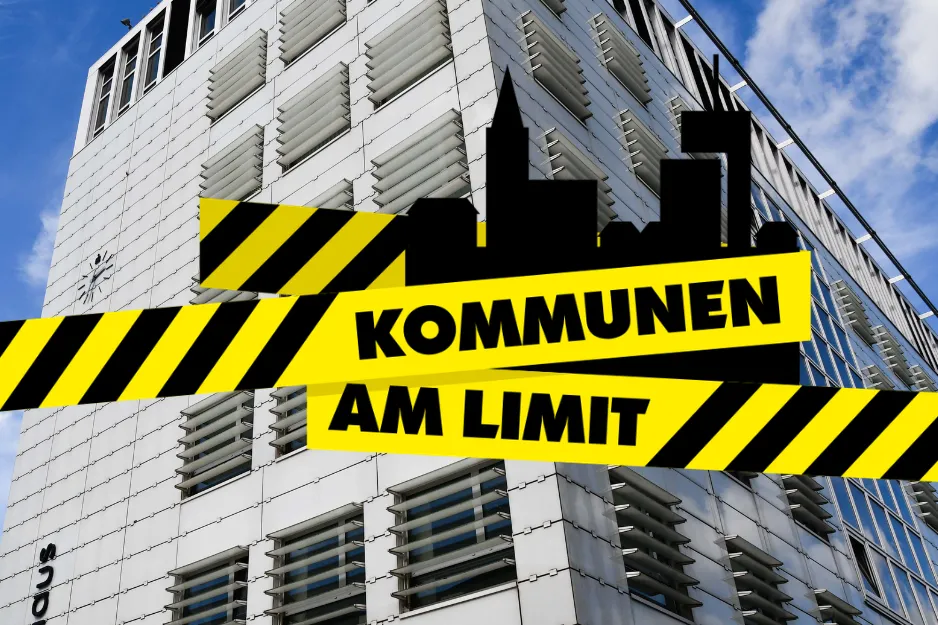 Gelbes Warnband mit der Aufschrift „KOMMUNEN AM LIMIT“ vor einem modernen Verwaltungsgebäude in Lüdenscheid. Der Aktionstag soll auf die angespannte kommunale Finanzlage aufmerksam machen.