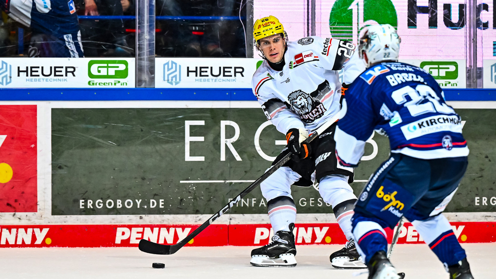 Eishockeyspieler Dennis Lobach mit dem Puck im Angriff für die Löwen Frankfurt, während ein Gegenspieler ihn stellt.