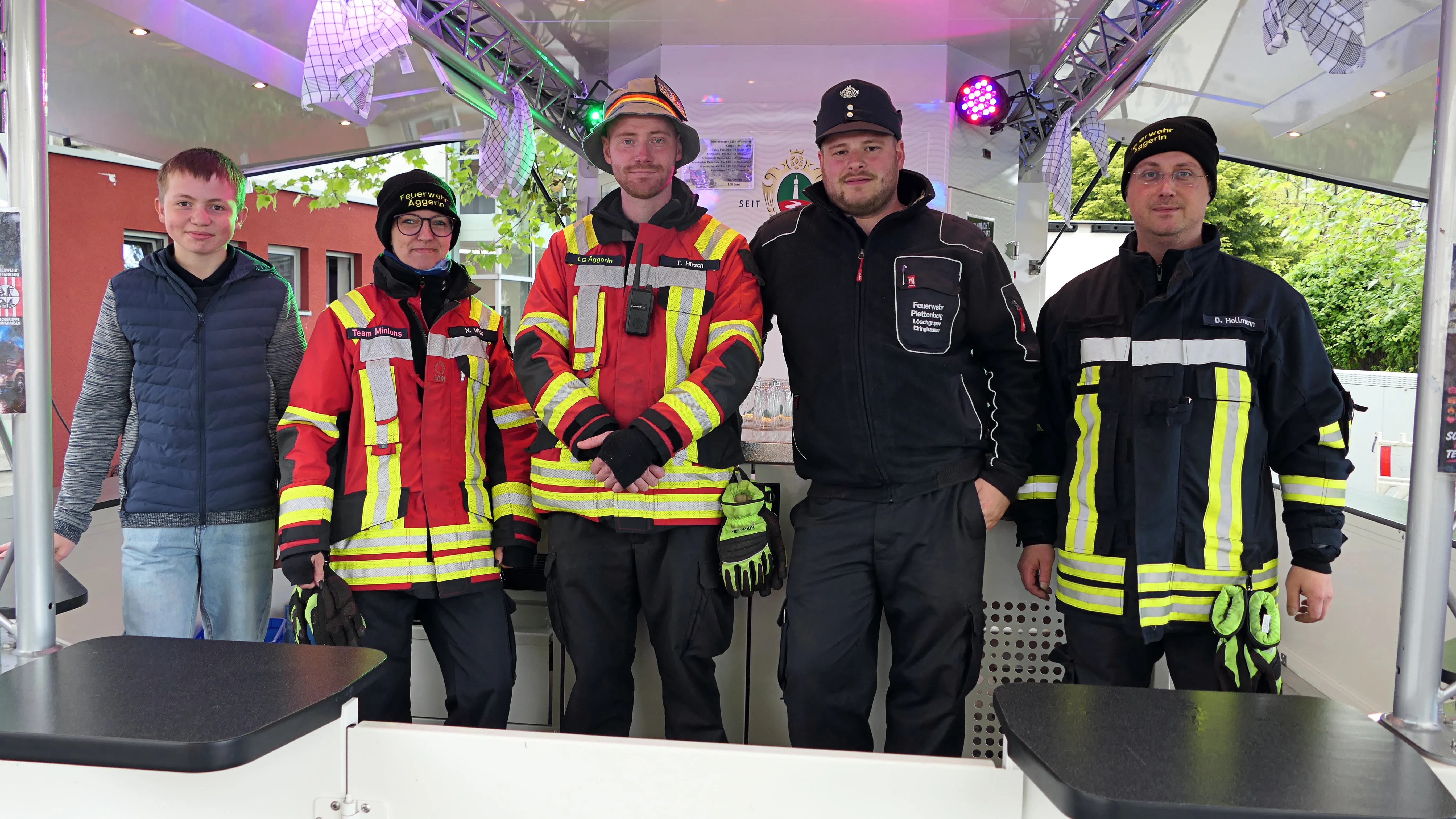 Fünf Personen in Feuerwehruniformen und ein Jugendlicher stehen vor einer beleuchteten Wand in einem Fahrzeug der Feuerwehr Eiringhausen.