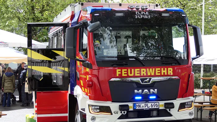 Roter und blauer Feuerwehrauto der Löschgruppe Eiringhausen mit geöffneter Fahrertür und der Aufschrift „FEUERWEHR“ am Kühlergrill.