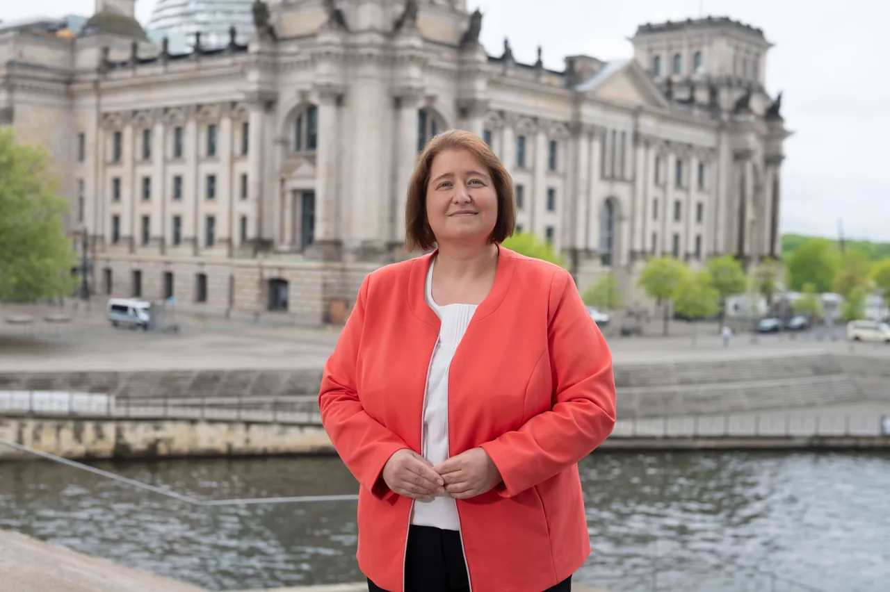 Bettina Lugk steht lächelnd vor dem Reichstagsgebäude in Berlin.