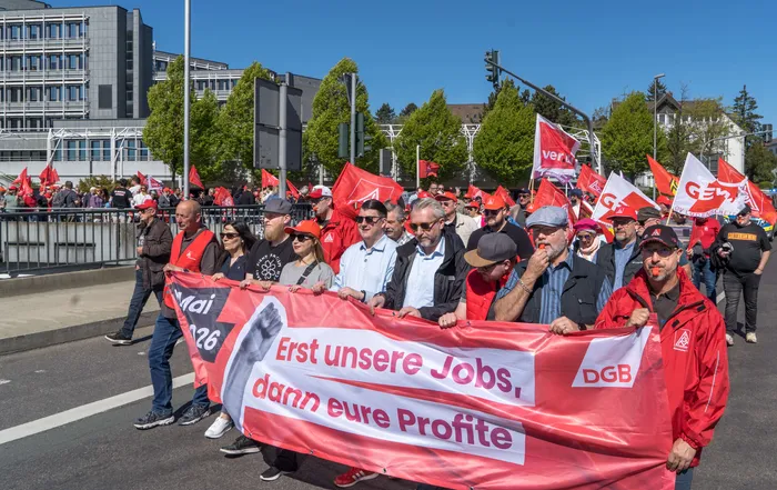 Demonstranten tragen ein Banner mit der Aufschrift „Erst unsere Jobs, dann eure Profite“ bei einer Mai-Kundgebung auf dem Lüdenscheider Rathausplatz.
