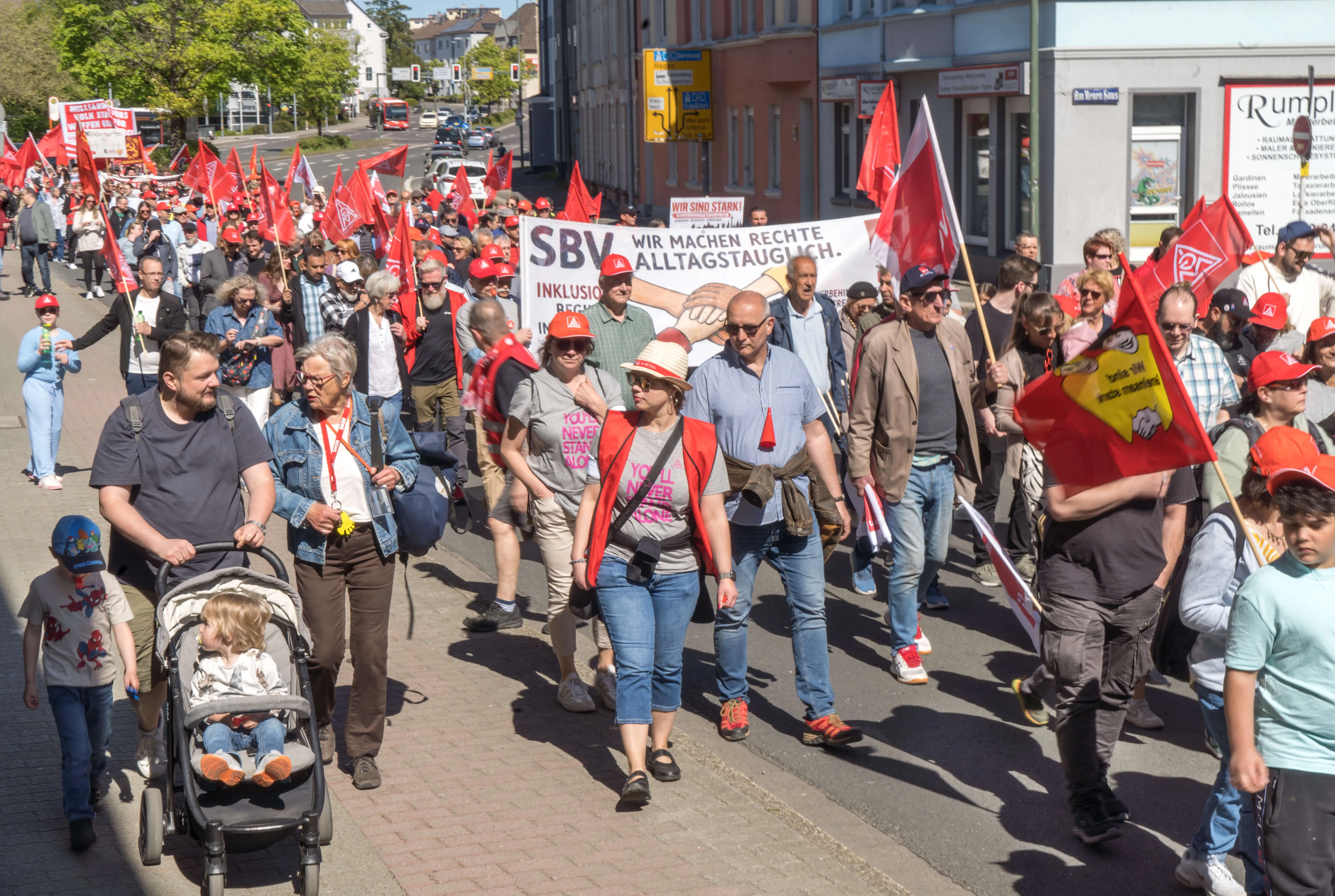 Demonstrationszug mit vielen Menschen, die rote Fahnen und Transparente mit der Aufschrift „SBV Wir machen Rechte alltagstauglich“ tragen.