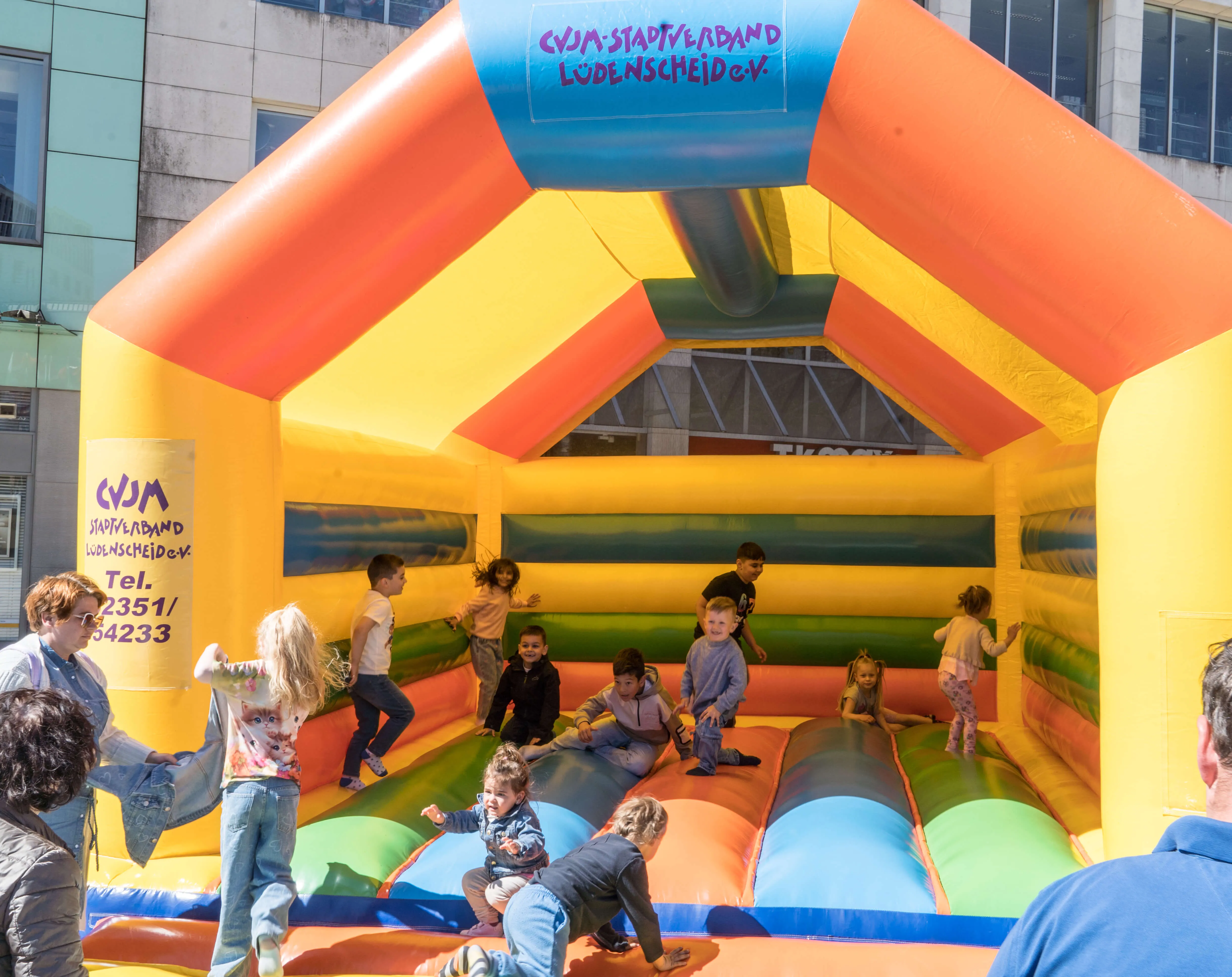 Mehrere Kinder spielen und klettern auf einer bunten Hüpfburg mit dem Logo des CVJM-Stadtverband Lüdenscheid e.V.