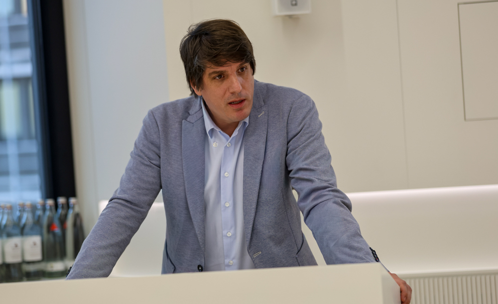 Manuel Huff von Die Linke, während er an einem Tisch sitzt und spricht.